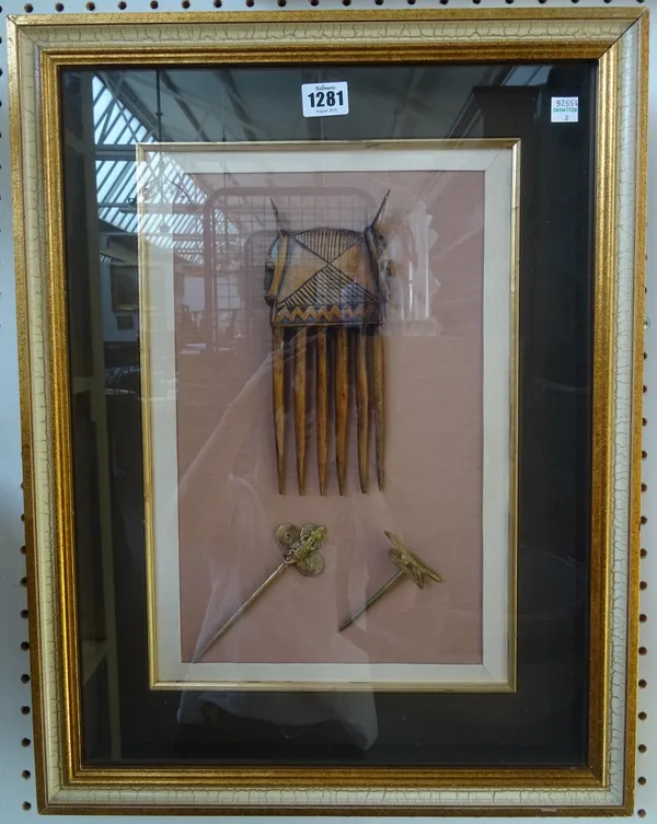 Tribal interest; African, Ivory coast, carved wooden comb, gilt metal hair pins, pan scales and weights, mounted in two glazed frames. 55cm x 43cm. (2