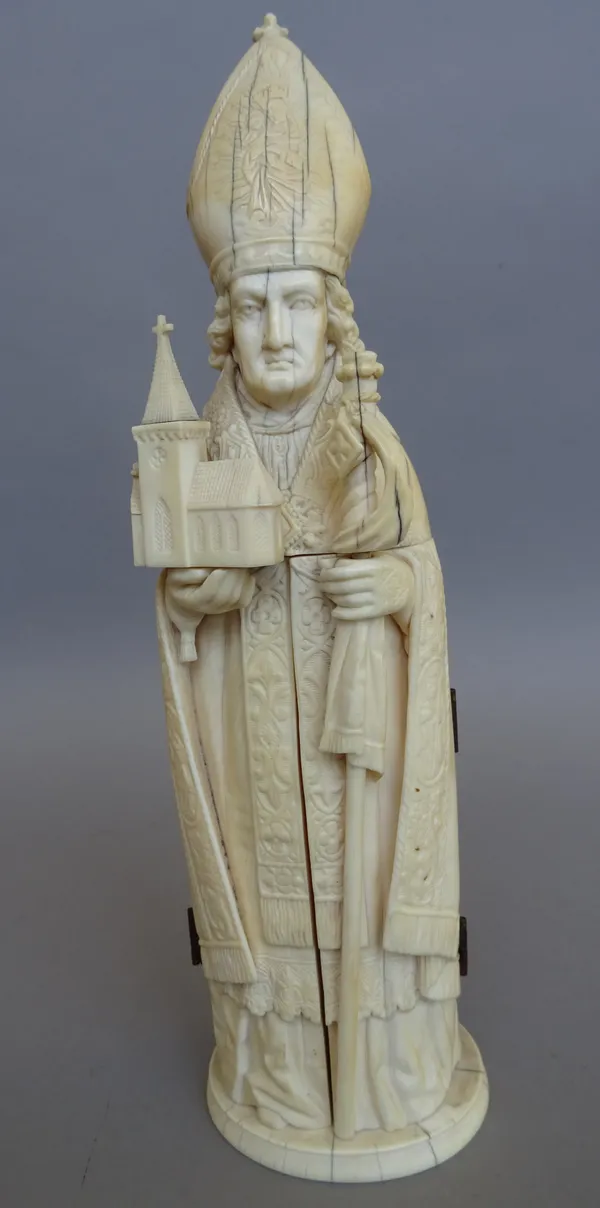 A Dieppe carved ivory figural triptych, 19th century, modelled as a Bishop holding a miniature church and ceremonial staff, his robe opening on hinged