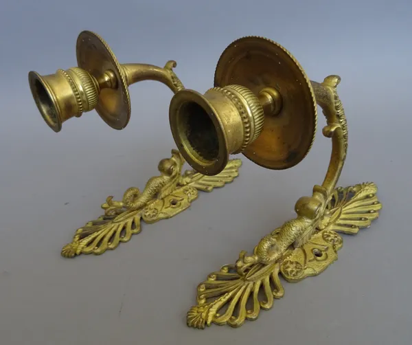 A pair of Regency ormolu wall appliques, each pierced anthemion backplate with dolphin and cast support issuing a foliate stem and single sconce, the