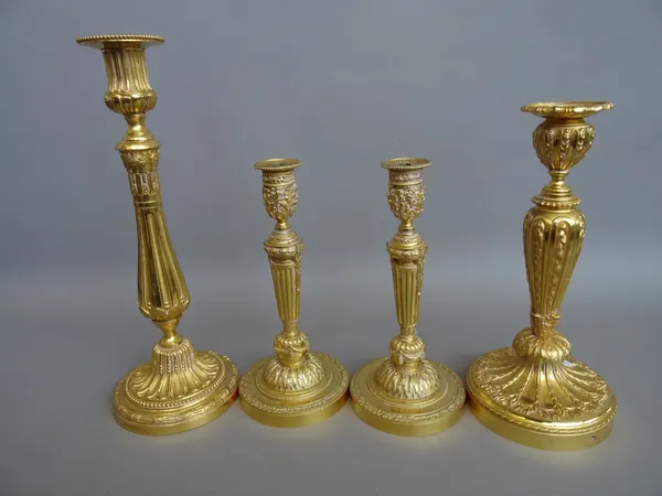 A pair of Louis XVI style French ormolu candlesticks, with foliate cast sconces and fluted tapering columns (24cm high) and two further Louis XVI styl