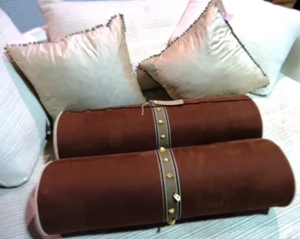 Cushions, a pair of 20th century brown suede bolster cushions with faux bone decoration and a pair of beige silk cushions with metal bead decoration (