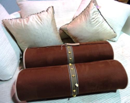 Cushions, a pair of 20th century brown suede bolster cushions with faux bone decoration and a pair of beige silk cushions with metal bead decoration (