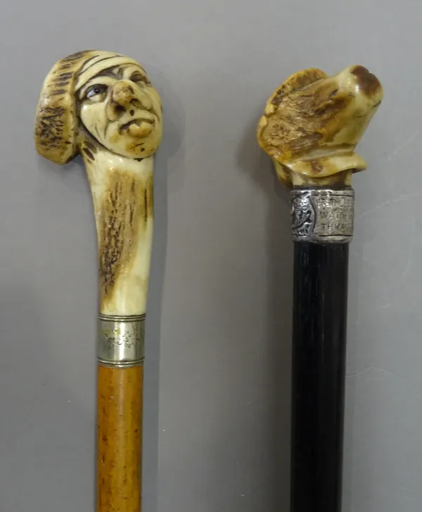 Two early 20th century antler mounted walking canes, each pommel naturalistically carved as a grotesque face, (79cm) (2).