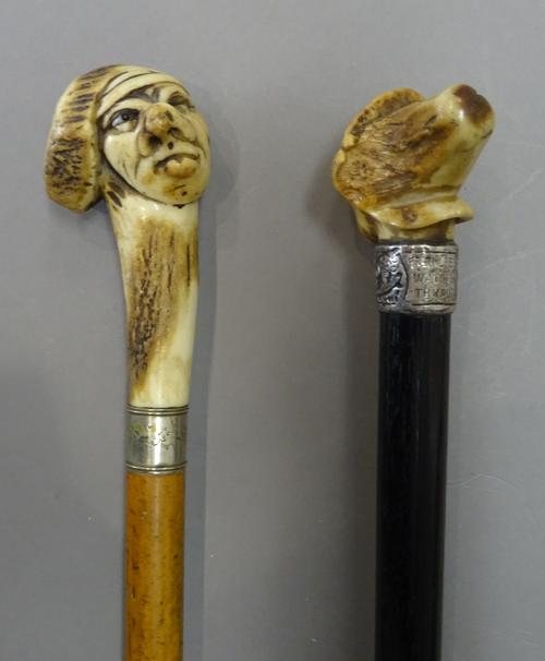 Two early 20th century antler mounted walking canes, each pommel naturalistically carved as a grotesque face, (79cm) (2).