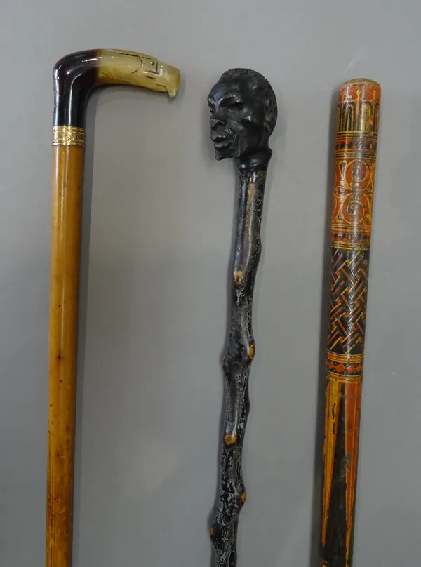 An unusual polychrome painted wooden walking stick, late 19th century, possibly Persian (98cm), a horn and brass inlaid 'eagle head' malacca walking s