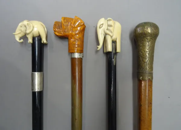 Two ivory topped 'elephant' walking canes, late 19th century, each on an ebonised cylindrical shaft (82.5cm) a composite 'dog's head' walking cane (88