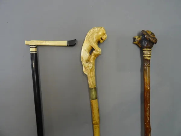 An antler mounted black thorn swagger stick, late 19th century, the antler pommel carved with a grotesque face (85cm), an African ebony and ivory walk