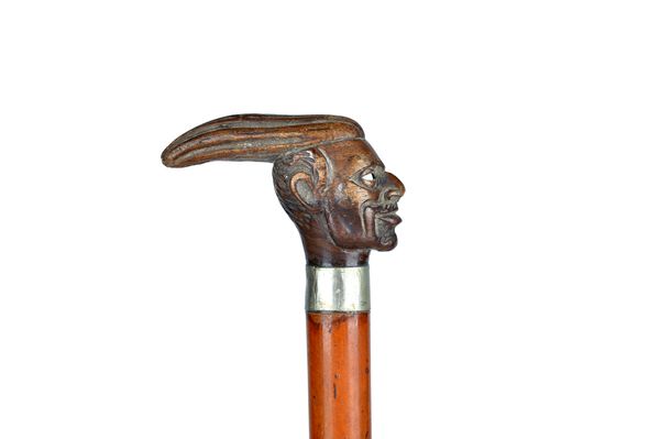 A horn mounted walking cane, 19th century, the handle carved as an African herdsman, over a gilt  metal collar and cylindrical hardwood shaft (87.5cm)