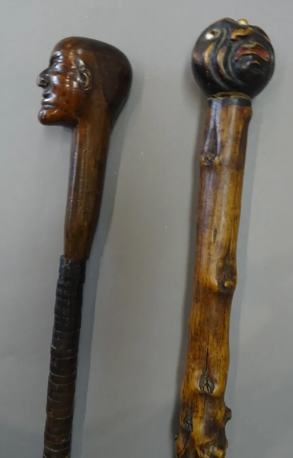 An unusual carved wood and leather bound walking stick, 19th century, the pommel carved as a man's head over a shaft decorated with leather washers (8