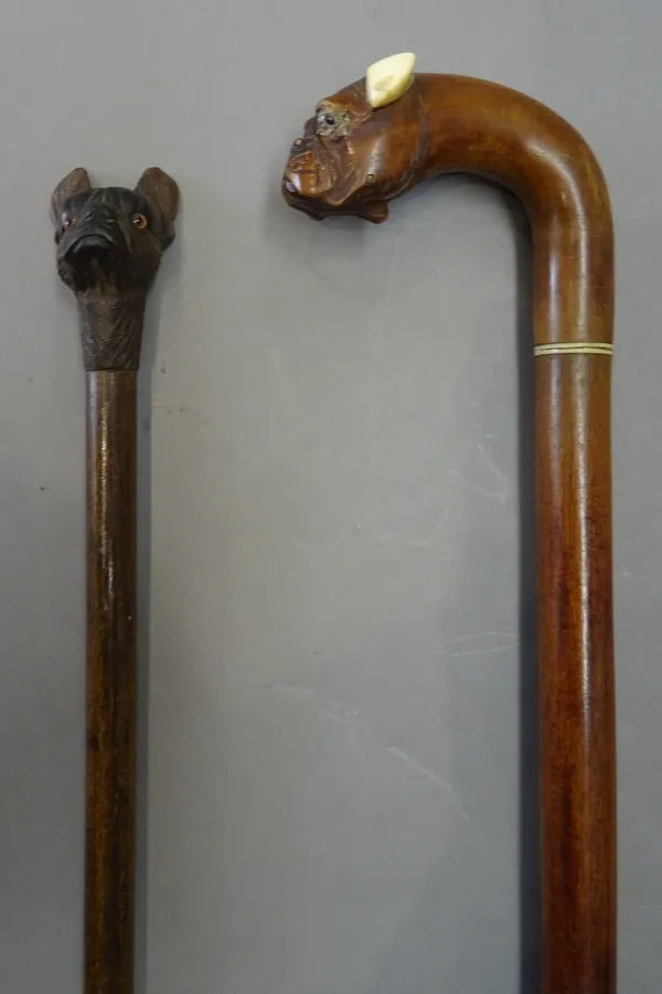 An ivory mounted fruitwood walking stick, circa 1900, the pommel carved with automated 'boxer dog' head (90cm) and a Black Forest swagger stick with c