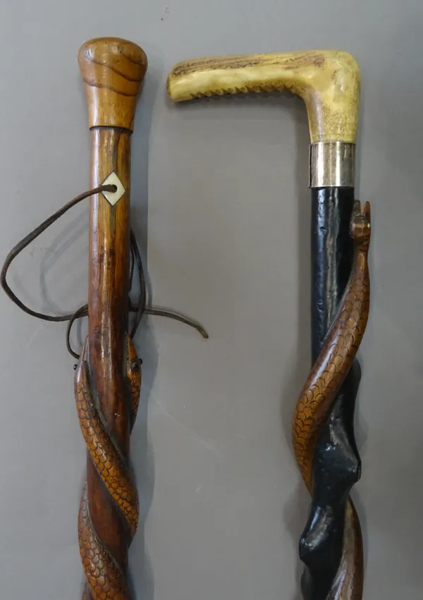 A carved wooden 'snake shaft' walking stick with a horn handle and silver collar (87cm) and another similar, with two entwined snakes carved to the sh