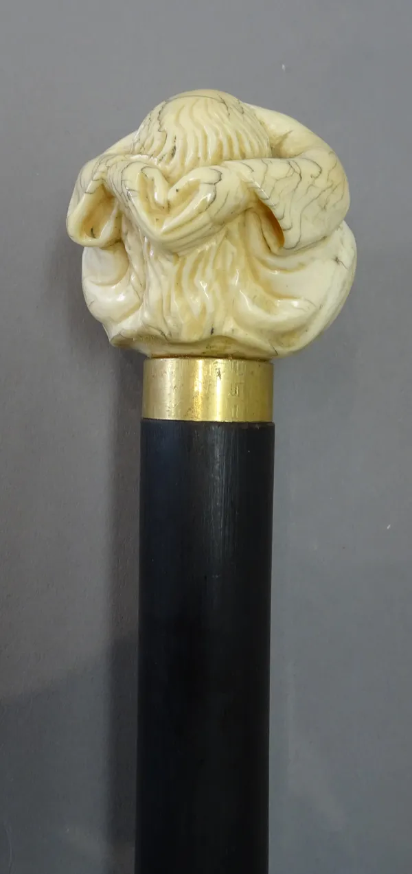 An early 19th century Japanese ivory figural walking cane pommel, modelled as a figure seated with head in hands, on a later ebonised shaft, (pommel 6