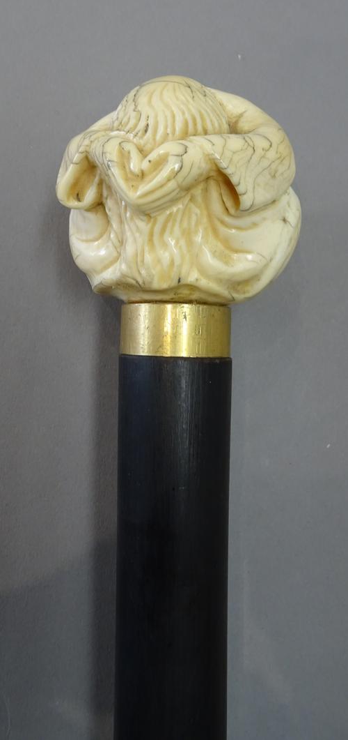 An early 19th century Japanese ivory figural walking cane pommel, modelled as a figure seated with head in hands, on a later ebonised shaft, (pommel 6