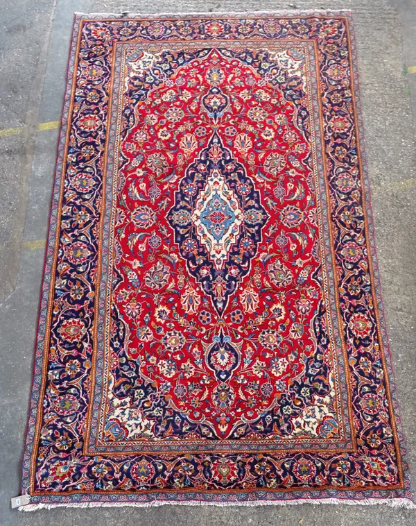 A Kashan carpet, Persian, the madder field with an elongated indigo medallion, matching spandrels, all with bold floral vines, an indigo complementary