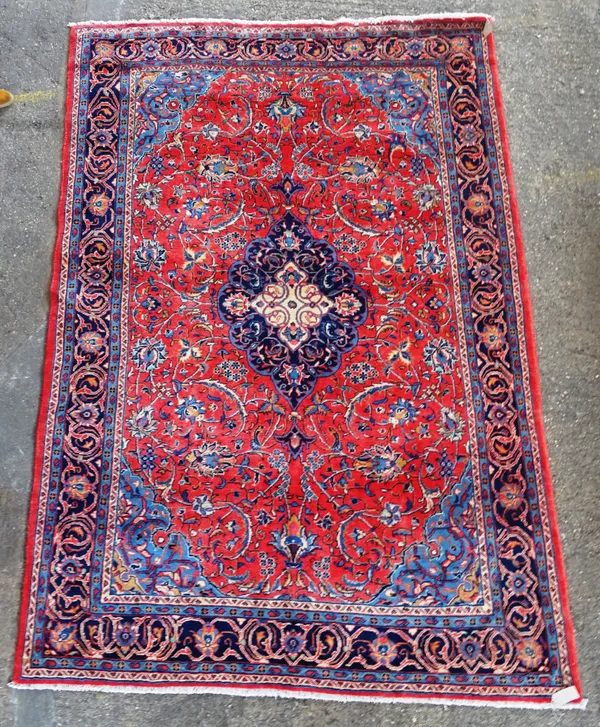 A Kashan carpet, Persian, the madder field with an indigo medallion, pale indigo spandrels, all with floral sprays, an indigo complementary border, 35