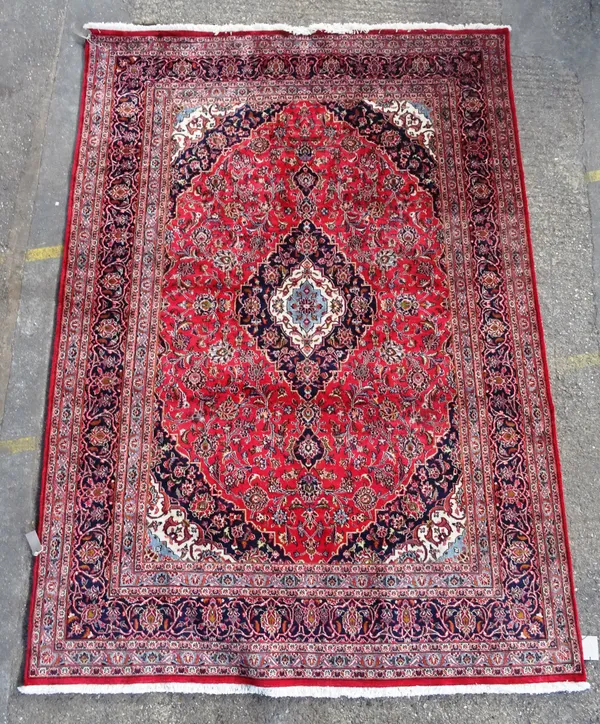 A Kashan carpet, Persian, the madder field with a dark indigo, ivory and light indigo medallion, matching spandrels, all with intricate floral sprays,