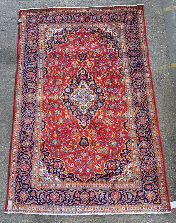 A Kashan carpet, Persian, the madder field with a shaped indigo and ivory diamond medallion, matching spandrels, all with delicate floral sprays, a da