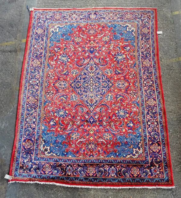 A Kashan carpet, Persian, the madder field with an indigo diamond medallion, pale indigo spandrels, all with bold floral sprays, an indigo palmette an