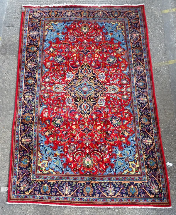 A Kashan carpet, Persian, the madder field with a shaped indigo medallion supported by palmette, pale indigo spandrels, all with floral sprays, a dark