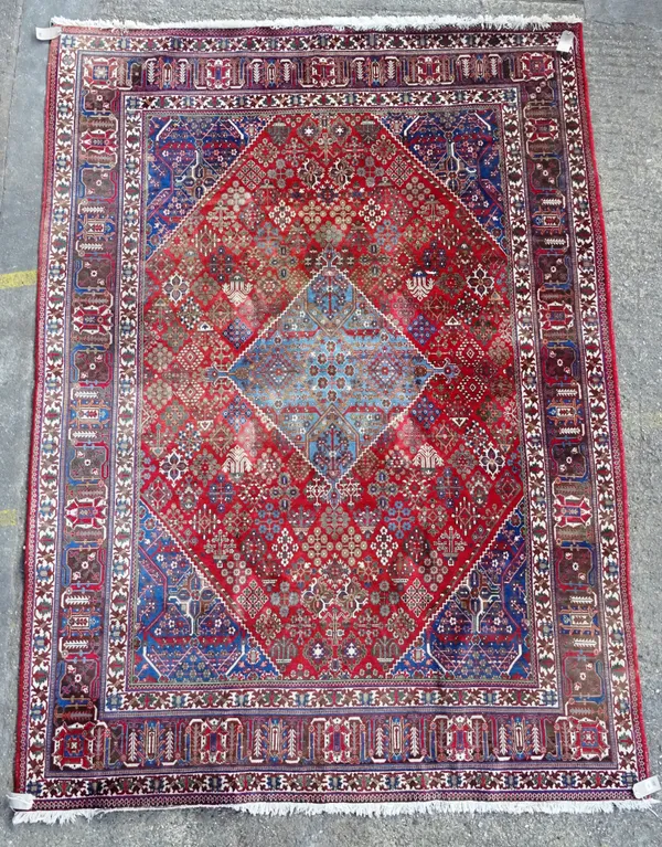A Joshaghan carpet, Persian, the madder field with central indigo medallion, all with diamond plant motifs, an indigo palmette and leaf border, 326cm