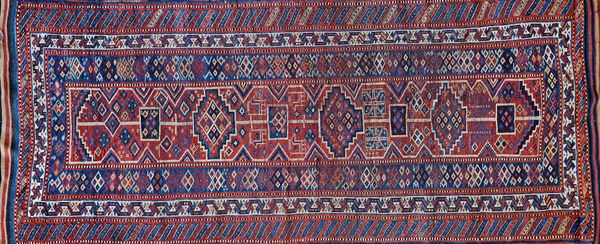 A Kurdish Afshar Kelleh, Persian, the indigo field with a madder panel with single medallions, two pairs of deer, two borders, 305cm x 130cm.