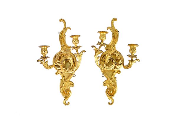A pair of Rococo Revival giltwood twin candle sconce wall brackets with opposing 'C' scroll back plates, 22cm wide x 43cm high (2). Illustrated