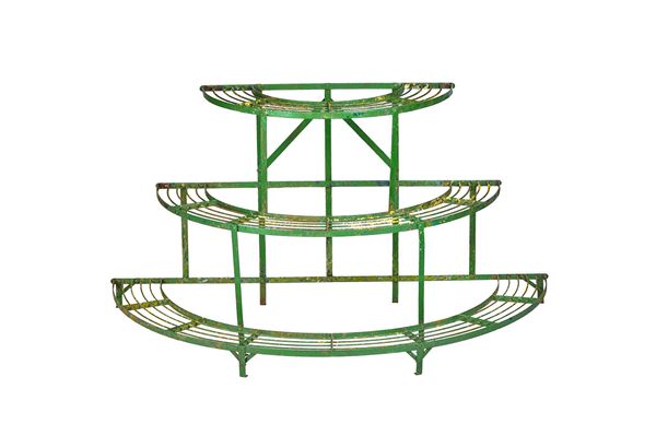 An early 20th century green painted wrought iron three tier graduated semi-elliptic plant stand, 142cm wide x 74cm high x 71cm deep.  Illustrated