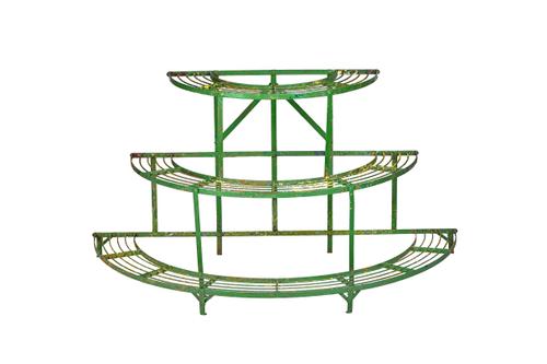 An early 20th century green painted wrought iron three tier graduated semi-elliptic plant stand, 142cm wide x 74cm high x 71cm deep.  Illustrated