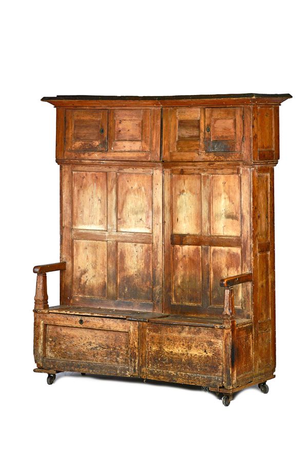 A George III pine, free standing, curved back bacon settle, with opposing panelled cupboards, above double lift top solid seat, 168cm wide x 200cm hig