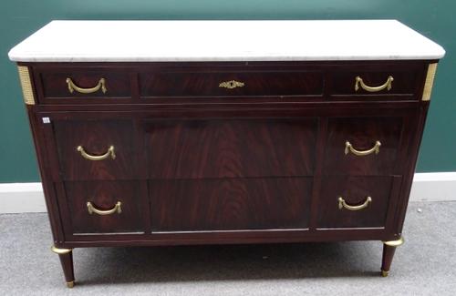 A Louis XVI style commode, the white marble top over a gilt metal mounted mahogany three drawer base, on tapering turned supports, 124cm wide x 86cm h
