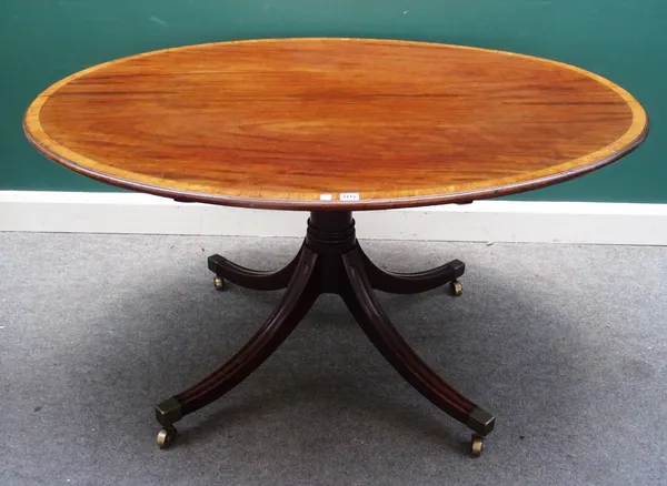 A George III crossbanded mahogany oval snap top centre table, on four downswept supports, 137cm wide x 72cm high x 102cm deep.