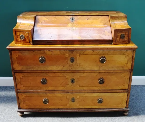 An 18th century South German marquetry inlaid bureau commode, the slope front superstructure flanked by drawers, the base with three long drawers on t