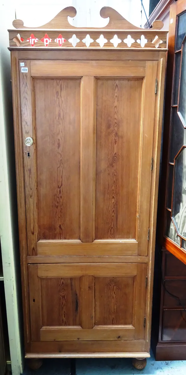 A Victorian pine cupboard with pierced cornice over a pair of double panelled cupboards, on bun feet, 78cm wide x 206cm high x 46cm deep.