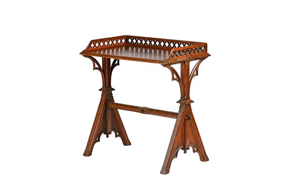 A Victorian Gothic revival oak writing table with pierced three-quarter gallery on pierced triangle supports, 81cm wide x 85cm high x 48cm deep. Illus