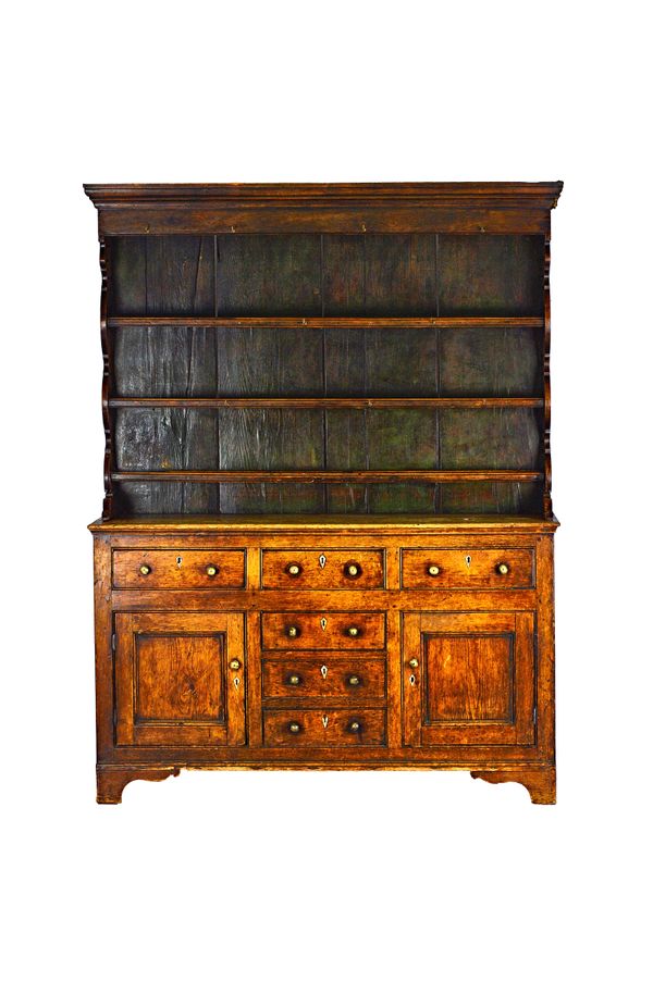 A George III waxed pine dresser, the enclosed three tier plate rack over six short drawers and a par of cupboards on bracket feet, 162cm wide x 202cm