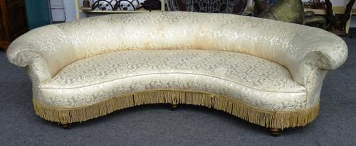 A 19th century kidney shaped Chesterfield style sofa with rollover back on turned gilt supports, 245cm wide x 65cm high.