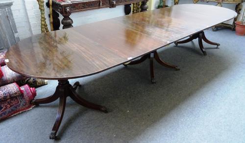 A George III style mahogany triple pillar extending dining table on twelve downswept supports, including  two extra leaves, 114cm wide x 248cm long x