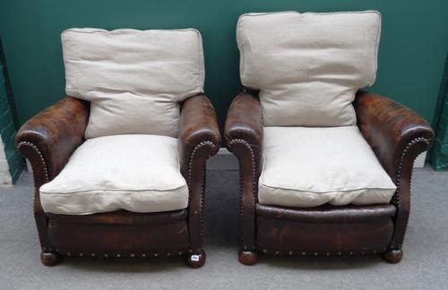A pair of mid-20th century studded brown leather upholstered easy armchairs on bun feet, 90cm wide x 86cm high (2).