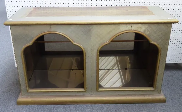 R. Dubarry; a 20th century brass veneered side cabinet, with a pair of arched recesses enclosing glass shelves, 136cm wide x 81cm high x 48cm deep.