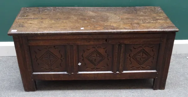 A 17th century oak coffer with plank top over a triple carved front panel on stile feet, 113cm wide x 51cm high x 46cm deep.