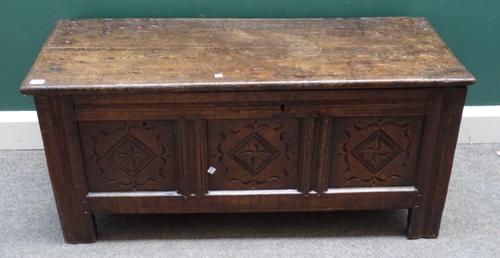 A 17th century oak coffer with plank top over a triple carved front panel on stile feet, 113cm wide x 51cm high x 46cm deep.