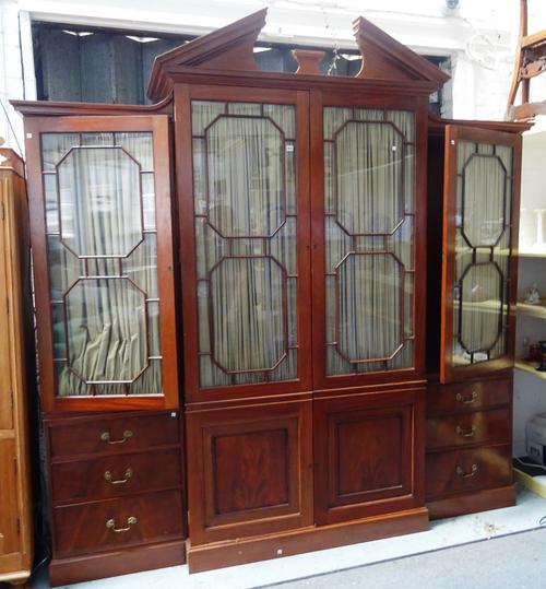 A George III style mahogany breakfront bookcase cabinet, the architectural cornice over four long astragal glazed doors, pair of cupboards and six sho