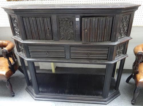 A 16th century and later oak buffet, the canted rectangular top with pair of cupboards and drawers flanked by blind tracery panels on six canted block