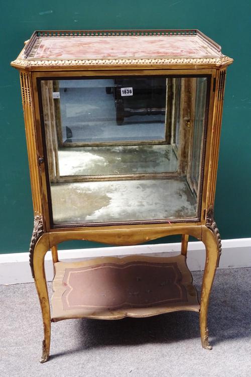 An early 20th century gilt framed vitrine cabinet with mirrored back glazed front and sides on scroll supports united by platform undertier, 60cm wide