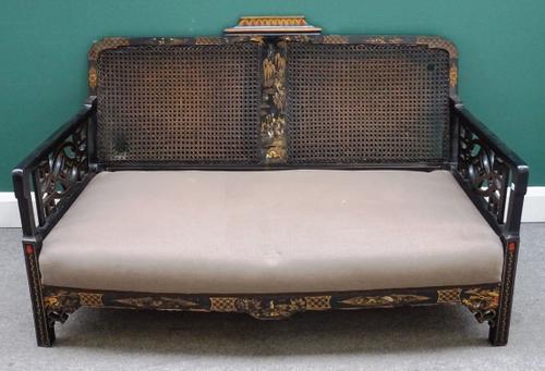 A 20th century black lacquer and chinoiserie decorated three piece suite with cane back and cockpen sides, sofa 141cm wide x 82cm high and a pair of m