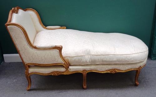 A Louis XV style gilt framed day bed, with semi-padded open arms, on six scroll supports, 165cm long x 84cm wide.