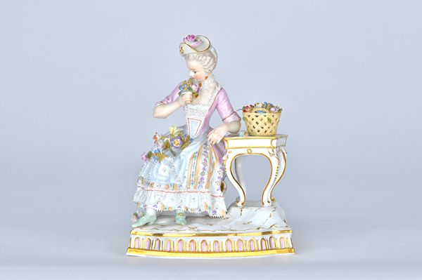 A Meissen porcelain figure of `Smell',  late 19th century, from a set of the Senses, modelled as a lady in a crinoline dress seated at a table with a