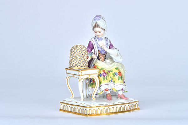 A Meissen porcelain figure of `Touch',  late 19th/early 20th century, from a set of the Senses, modelled as a lady in crinoline dress seated at a tabl