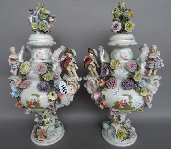 A pair of Sitzendorf two-handled vases and covers, circa 1900, encrusted in high relief with flowers and painted each side with a vignette of lovers i