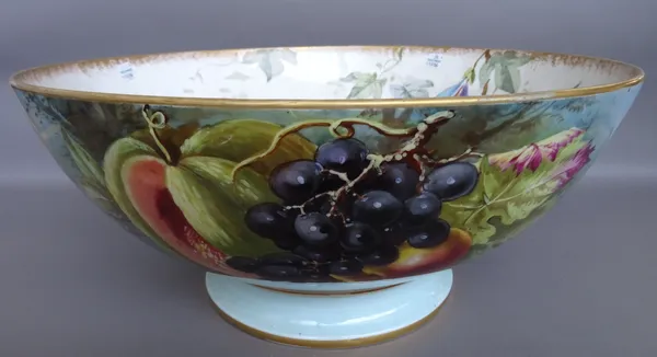 A Limoges porcelain footed bowl, 20th century, of large proportions, hand painted with fruit against a riverscape, red printed mark. 44.5cm diameter.